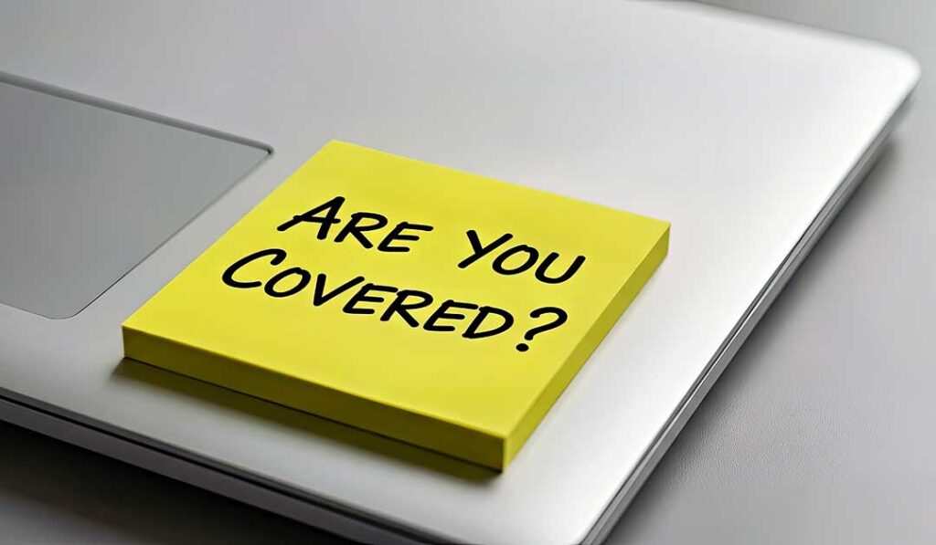 A person reviews a cancellation notice and insurance documents at a kitchen table with a laptop.